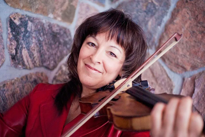 Cindy Thompson smiling and playing her fiddle.